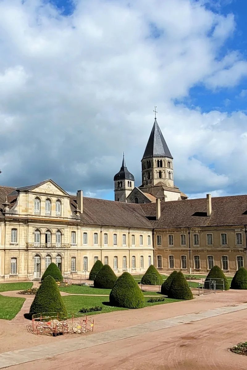Il transetto meridionale superstite e il campanile ottagonale Clocher de l'Eau Bénite dell'Abbazia di Cluny che si ergono sopra i tetti della cittadina di Cluny, nella Borgogna meridionale, Francia, nella calda luce del pomeriggio.